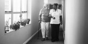 Senior women walking with nurse at nursing home.