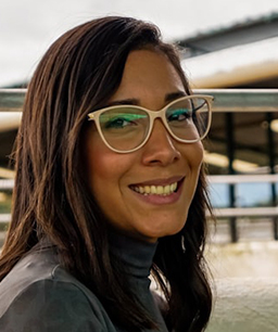 Young woman with long hair and glasses smiling