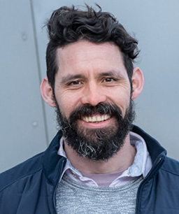 Guy with curvy hair and black beard smiling