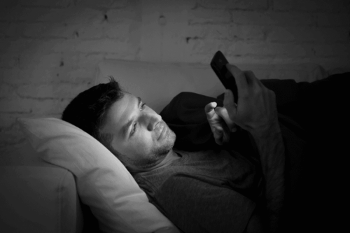 Man lying in bed and typing on the phone