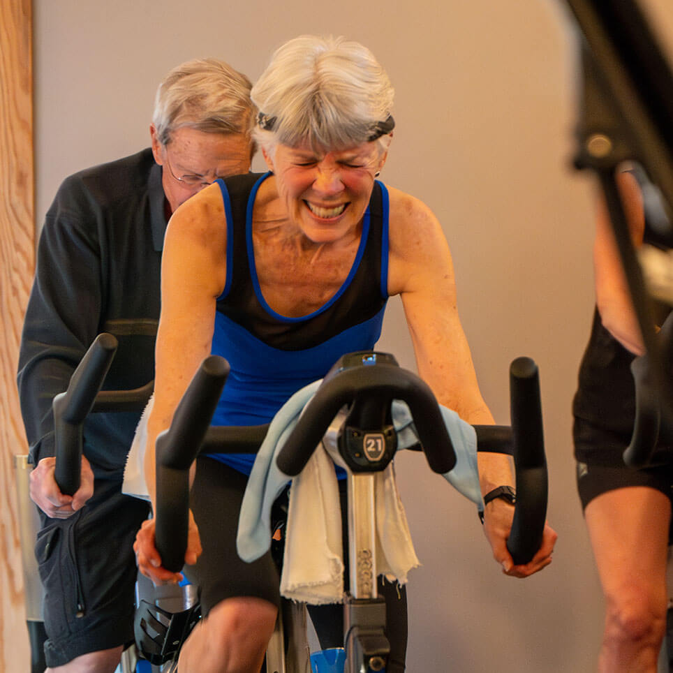 A cyclist on a stationary bicycle squinting while working hard